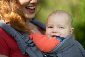 Mama wandelt met baby in draagzak, lachende baby in draagzak bij ouder