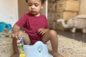 Peuter zit op het potje tijdens zindelikheidstraining en speelt ondertussen met blokken