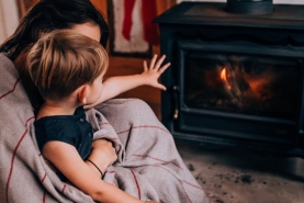 Mama en zoon zitten gezellig voor kachel in de warmte op veilige afstand