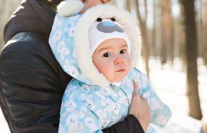 Baby ingeduffeld in winterjas in sneeuwlandschap