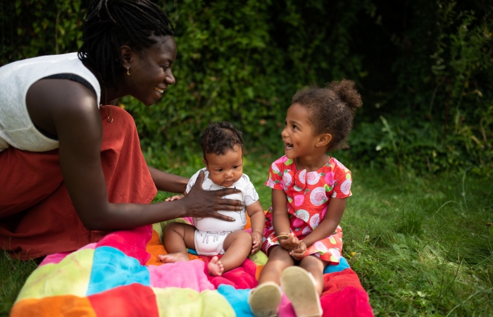 Mama tilt speelt met baby en peuter buiten in de tuin, buiten spelen, dekentje