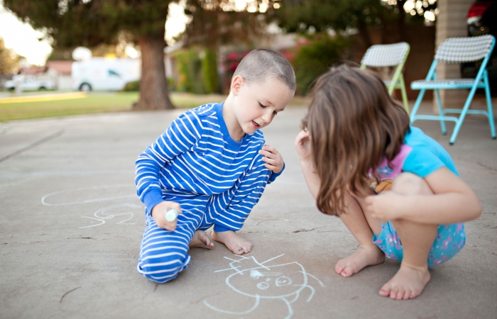 Twee kinderen spelen buiten met stoepkrijt