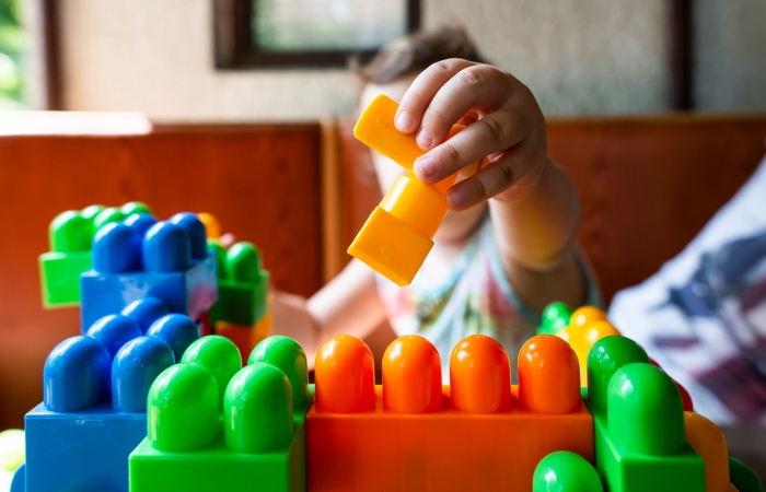 Kind speelt met felgekleurde blokken in de kinderopvang, bouwen met blokken