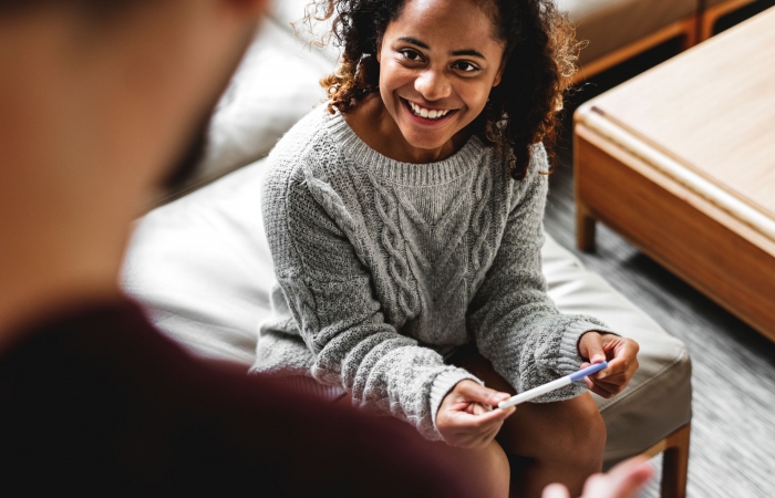 Een jonge vrouw bespreekt een positieve zwangerschapstest met haar partner