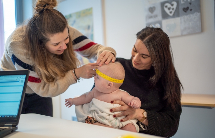 Een verpleegkundige meet de hoofdomtrek van een baby tijdens het consult