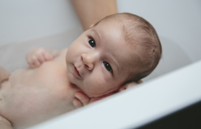 Ouder geeft baby een bad, baby onderdompelen, bad geven