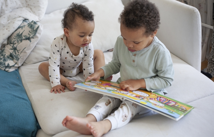 Zus en broer lezen in boekje op de zetel