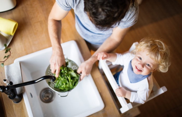 Papa kookt samen met kleuter, groenten wassen in de keuken