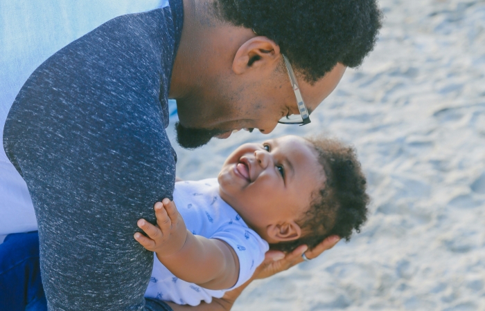 Papa en baby knuffelen op het strand