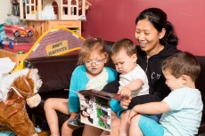 mama Angelic zit met de kindjes in de zetel en leest een boekje voor, gezin samen in de zeten met een boek