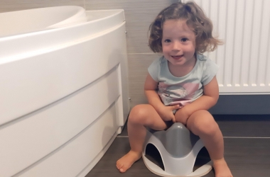 Lachend meisje zit op het potje in de badkamer