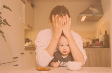 opvoedstress oranje, mama zit met hoofd in haar handen, baby op schoot