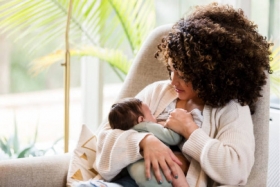 Mama geeft borstvoeding aan baby in zetel