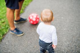 Een peuter speelt buiten met de bal