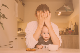 opvoedstress oranje, mama zit met hoofd in haar handen, baby op schoot