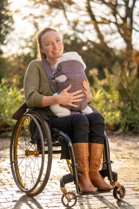 Vrouw in rolstoel met kind in draagzak