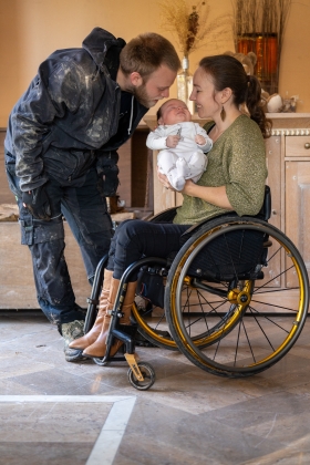 Vrouw in rolstoel met kind op de arm en haar man