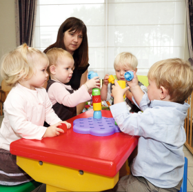 onthaalmoeder speelt met kindjes aan tafel