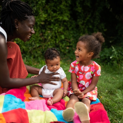 Mama tilt speelt met baby en peuter buiten in de tuin, buiten spelen, dekentje