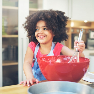 Lachend meisje met kroeshaar roert in pot