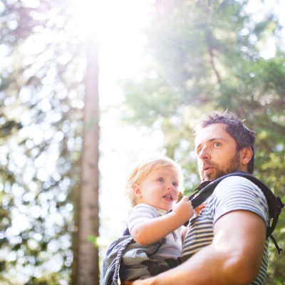 Papa draagt kindje in draagzak tijdens wandeling in het bos