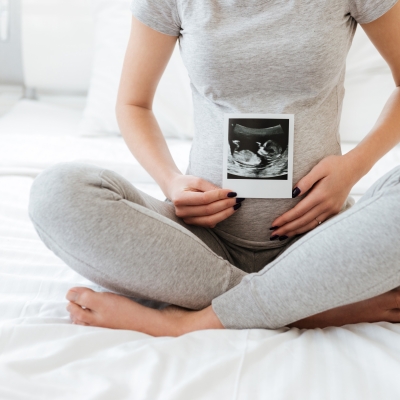 Mama houdt echografie voor haar zwangere buik, zwangere vrouw op bed