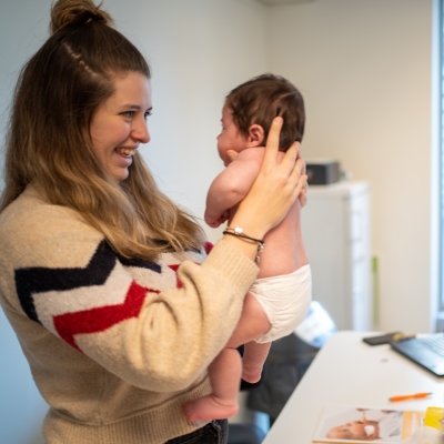 Een verpleegkundige houdt een baby vast op een consultatie