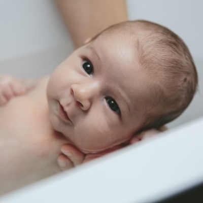 Ouder geeft baby een bad, baby onderdompelen, bad geven