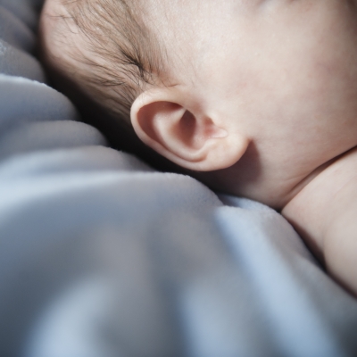 Close-up van het oor van een op het bed liggende baby