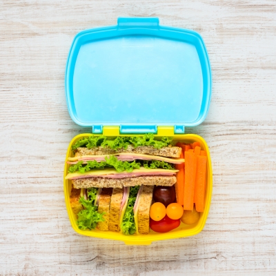 Gezondde brooddoos gevuld met boterhammen met ham en kaas, tomaten en wortel