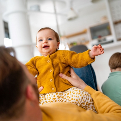 papa speelt met baby, peuter zit op de achtergrond en maakt geen contact