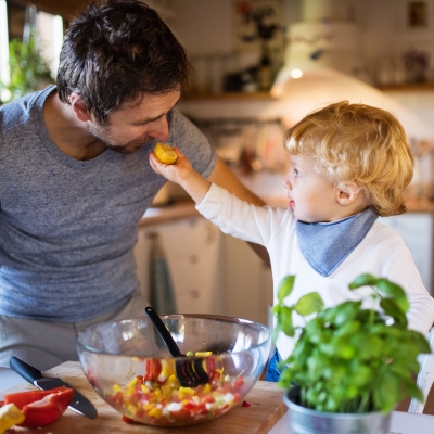 Papa en peuter koken samen groenten in de keuken