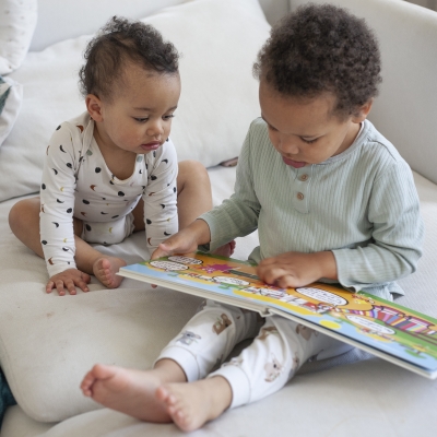 Zus en broer lezen in boekje op de zetel