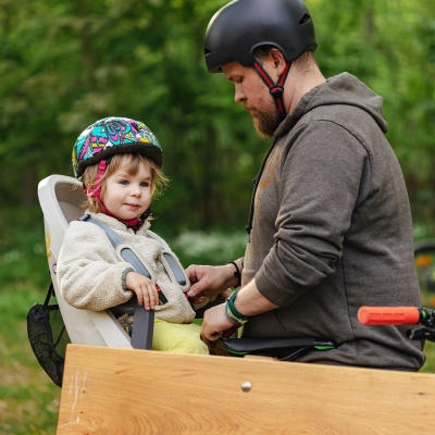 vader met baard en helm maakt kind vast op bakfiets