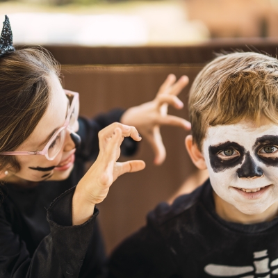 Zus en broer griezelen in hun verkleedoutfit voor Halloween