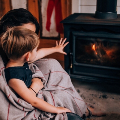 Mama en zoon zitten gezellig voor kachel in de warmte op veilige afstand