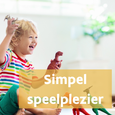 Kind zit lachend op grond en speelt met dino's