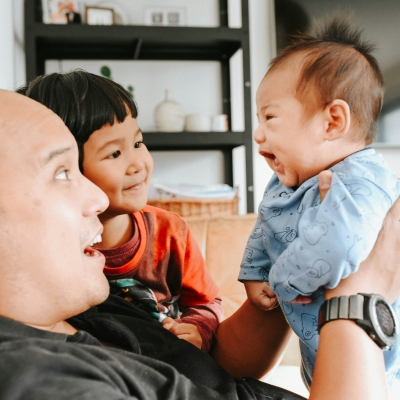 Papa zit met peuter en baby in de zetel en genieten van een gezellig babbelmomentje