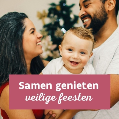 lachende mama en papa met peuter voor kerstboom