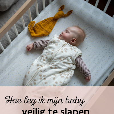 Baby slaapt in bedje op rug slaapzak 