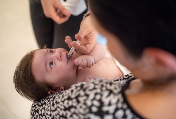 Een baby krijgt een oraal toegediend vaccin in het consultatiebureau