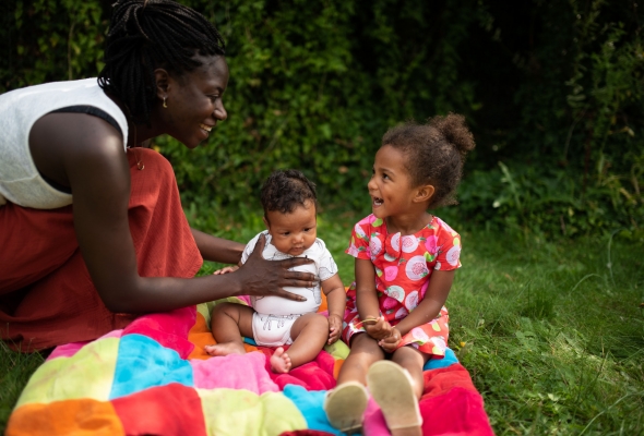 Mama tilt speelt met baby en peuter buiten in de tuin, buiten spelen, dekentje