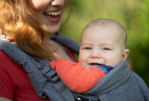 Mama wandelt met baby in draagzak, lachende baby in draagzak bij ouder