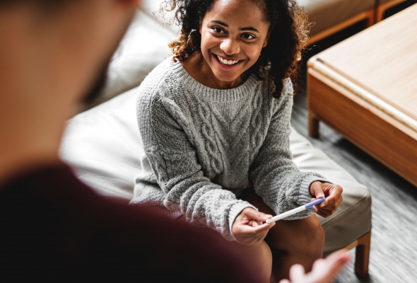 Een jonge vrouw bespreekt een positieve zwangerschapstest met haar partner