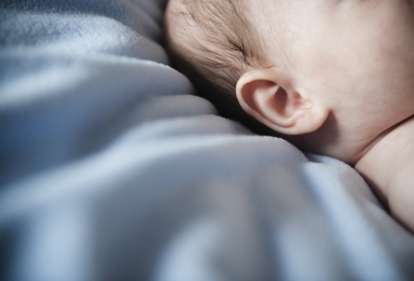 Close-up van het oor van een op het bed liggende baby