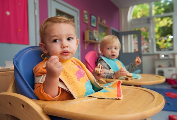 kindjes eten boterhammen in hun eetstoel in de crèche