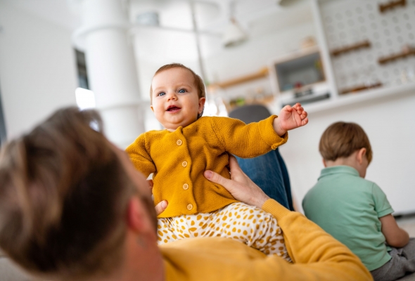 papa speelt met baby, peuter zit op de achtergrond en maakt geen contact