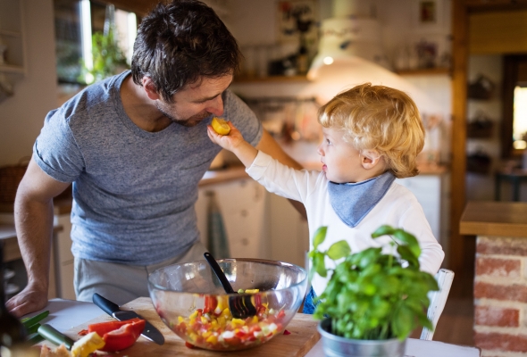 Papa en peuter koken samen groenten in de keuken