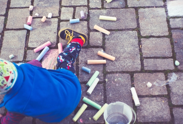 kind speelt met stoepkrijt