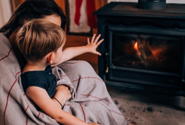 Mama en zoon zitten gezellig voor kachel in de warmte op veilige afstand